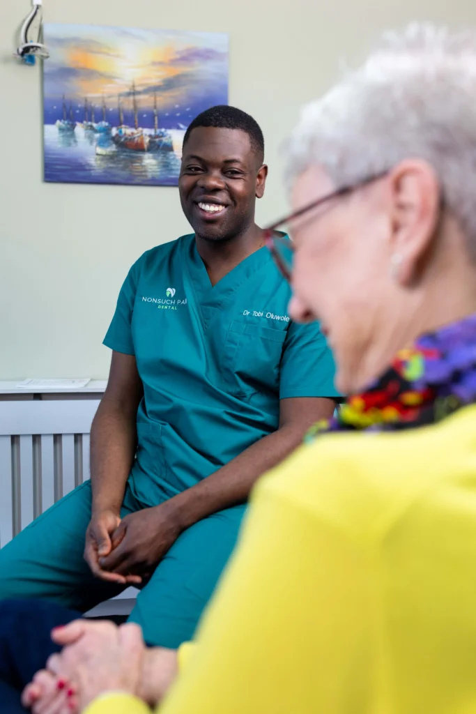 A dentist smiling while interacting with a patient at nonsuch park dental clinic.